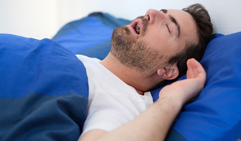 Man in bed snoring and suffering for sleep apnea syndrome